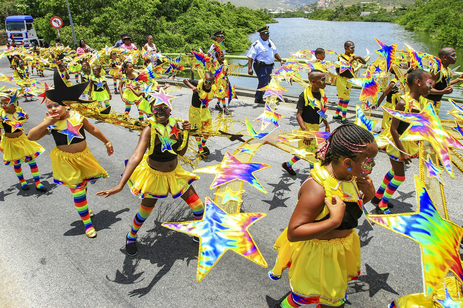 Lines of children dressed in yellow stars walk over a bridge in Phillipsburg, St Maarten